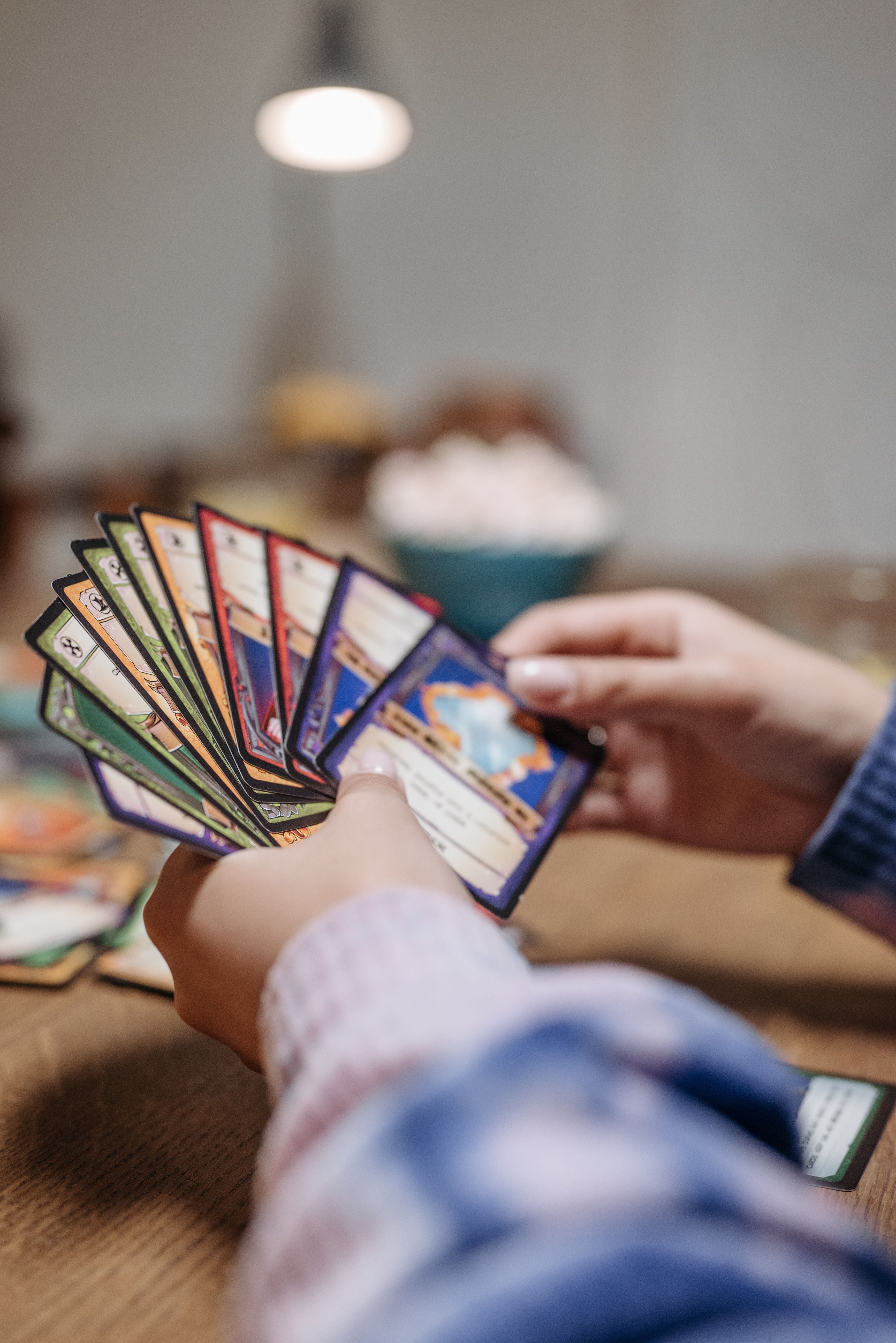 Two players holding anime trading cards during a card game